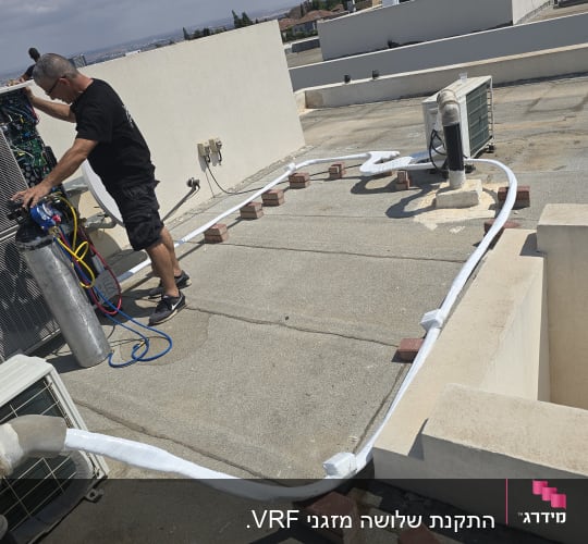 אדם עובד על מערכת מיזוג אוויר על גג